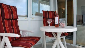 A room with two striped red and orange chairs, a white table, a bottle of wine, and a glass. - Frische Brise (Cuxhaven)
