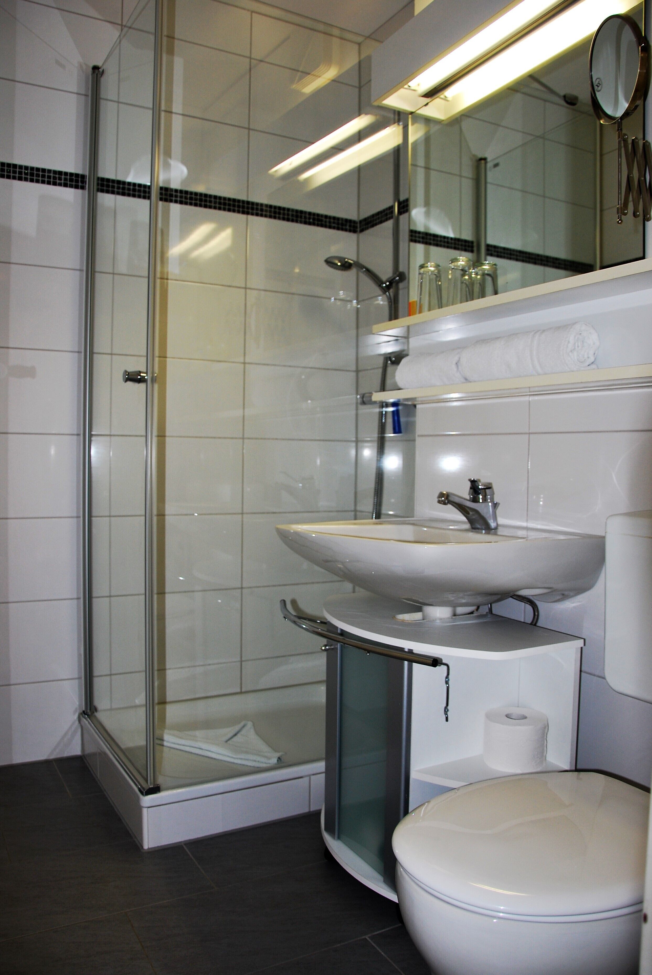 Un baño moderno con cabina de ducha de vidrio, un lavamanos blanco y un inodoro.