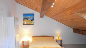 Ein Schlafzimmer mit einem hölzernen Bett, zwei Nachttischlampen, einem Gemälde an der Wand und einer weißen Tür.