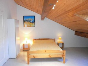 Una camera da letto con un letto di legno, due lampade sui comodini, un quadro appeso e una porta bianca.