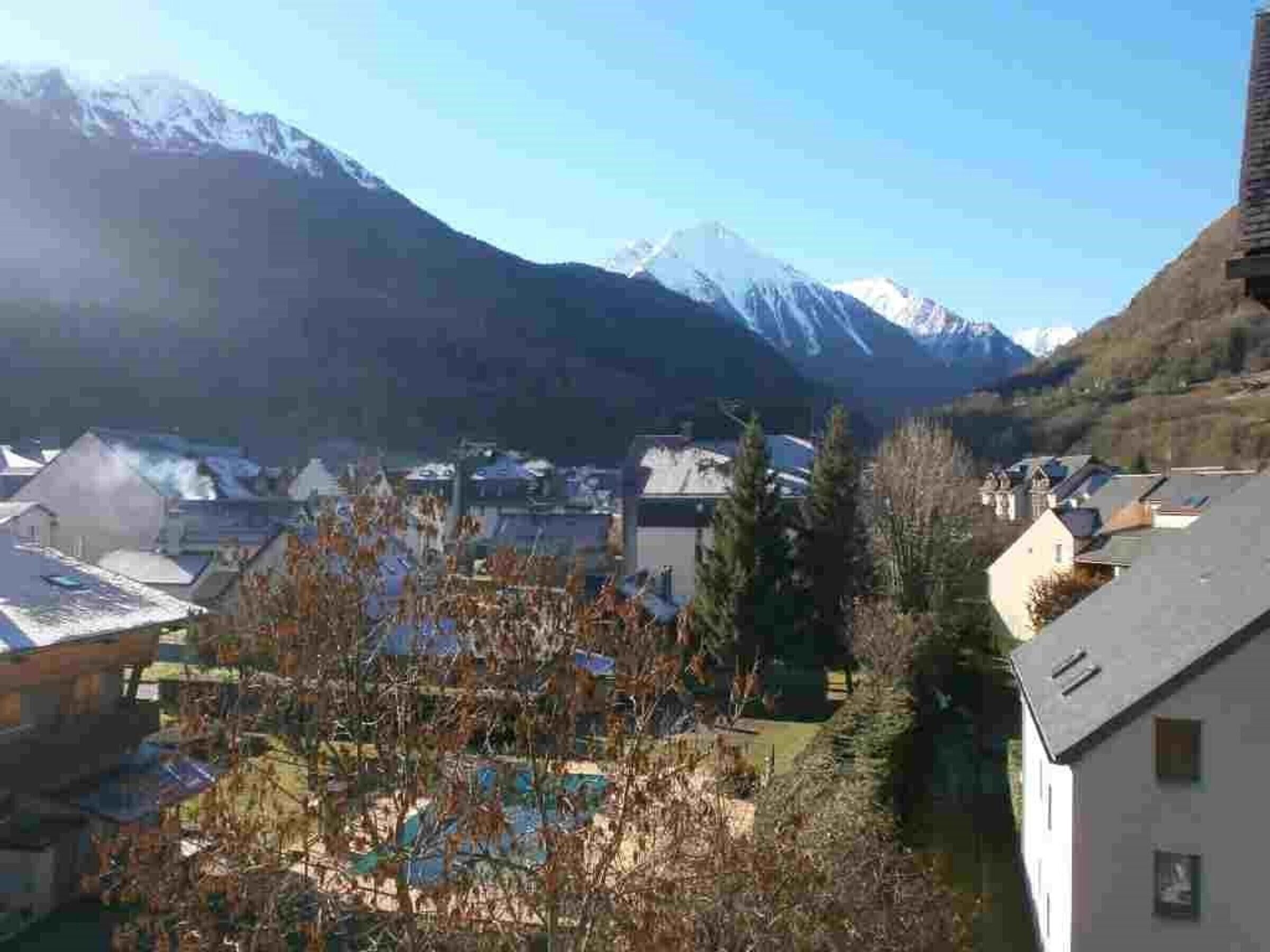 Un quartier résidentiel avec des maisons, une piscine et, en arrière-plan, des montagnes enneigées.