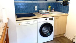 A compact kitchen with a washing machine, a microwave, and a sink.