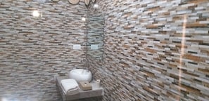 A bathroom with a modern mosaic tile wall, a sink with a mirror, and a towel.