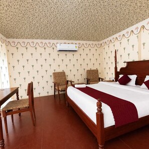 A hotel room with a bed, two chairs, a table, and a patterned wallpaper. - Vacation Village Luxury Tent - A Unit Of Braham Vatika Resort (Pushkar)