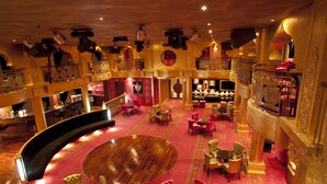 Un hall d’hôtel luxueux, doté d’un magnifique plancher circulaire en bois, de plusieurs espaces aménagés pour s’asseoir et d’une décoration somptueuse.