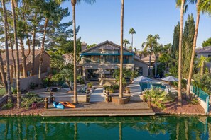 A resort with a pool, lounge chairs, and palm trees.