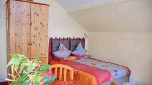 A bedroom with a bed, a wooden wardrobe, a dining table with chairs, and a potted plant. - Calm rental for 2 persons, the Blue House in Alsace, in a nice medieval village. (Bergheim)