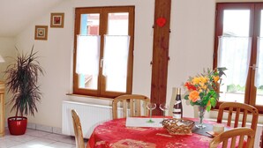A dining area with a red tablecloth, wooden chairs, a vase with flowers, and a bottle of wine. - Calm rental for 2 persons, the Blue House in Alsace, in a nice medieval village. (Bergheim)