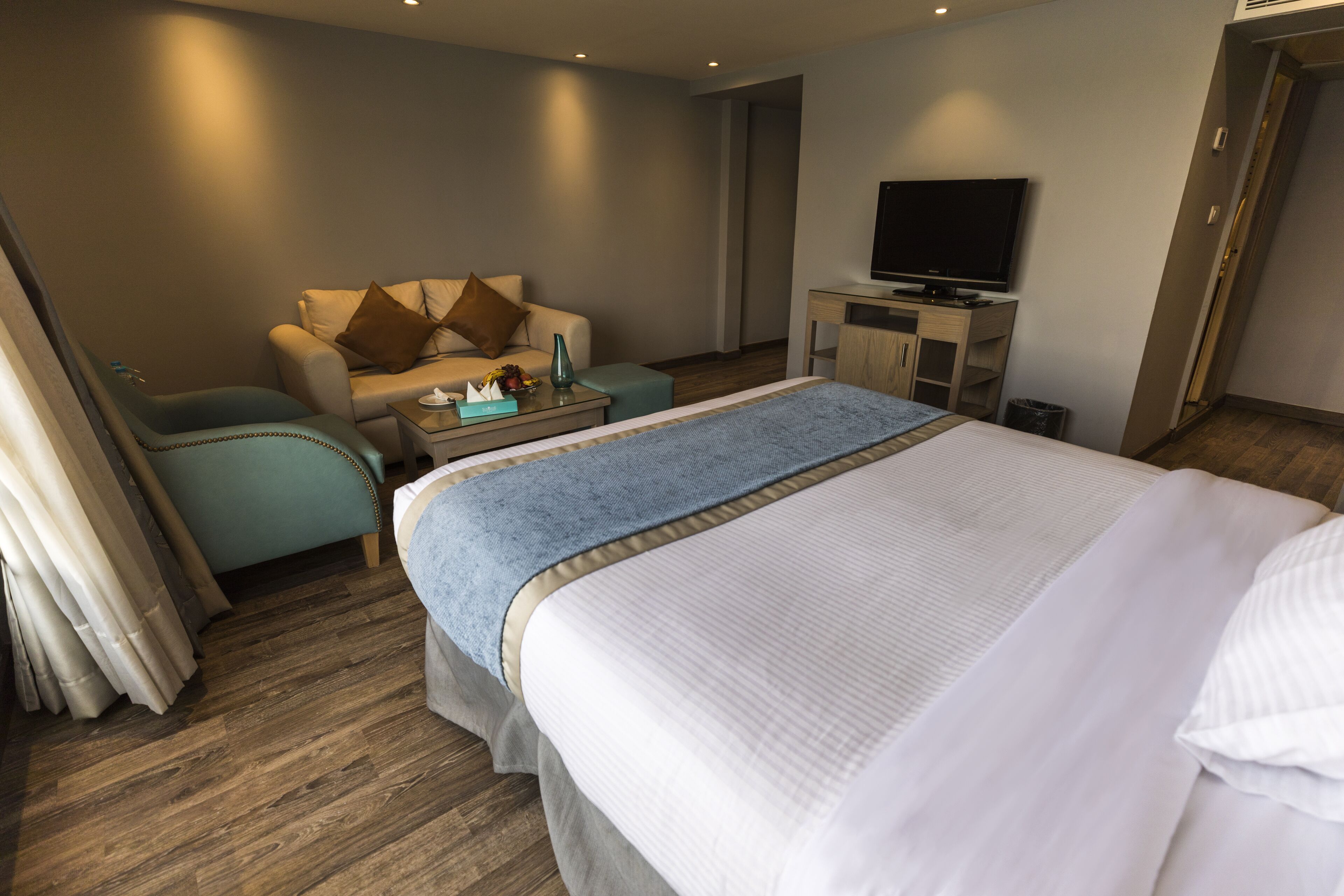 A hotel room with a large bed, a sofa, a television, and a small table.