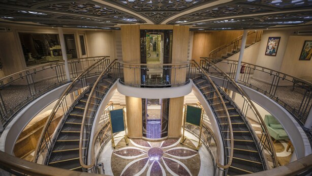 A multi-level atrium with a central staircase, decorative ceiling, and a view of the lobby area. - SUNRISE Semiramis I Cruise (Luxor)