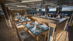 A restaurant with tables set for dining, wooden flooring, and a view of the sea. - SUNRISE Semiramis II Cruise (Luxor)