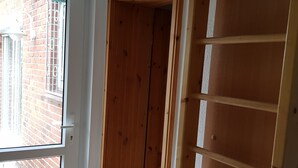 Um quarto com uma janela grande, uma porta de madeira e piso ladrilhado.