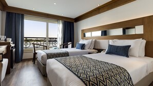 A hotel room with two beds, a desk, and a balcony with a view. - SUNRISE Semiramis III Cruise (Luxor)
