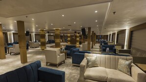 A spacious hotel lobby with multiple seating areas, including sofas and armchairs, and a central column with a unique design. - SUNRISE Semiramis III Cruise (Luxor)
