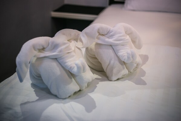 Two neatly folded towels on a white bed. - Loft Vintage Chalet Resort (Ko Lanta)