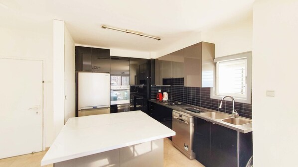 A compact kitchen with a white countertop, a built-in oven, a dishwasher, and a sink.