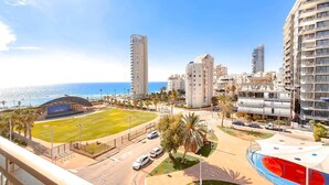 A coastal urban area with high-rise buildings, a sports field, and a swimming pool. - Charming 3bdr apt with sea view B5 (Bat Yam)