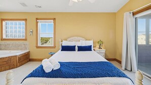 Un dormitorio con cama, ventana, mesita de noche, lámpara y baño con bañera.