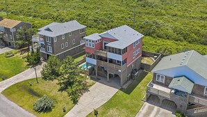 A residential area with multi-story buildings, a swimming pool, and a view of a natural landscape. - The After Glow | 940 ft from the beach | Private Pool, Hot Tub (Nags Head)