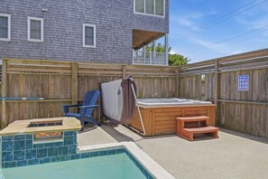 Een achtertuin met zwembad, jacuzzi en houten terras.