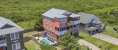 A multi-story residential building with a pool, surrounded by greenery.