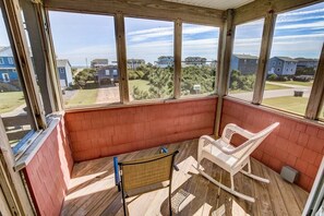 A room with a wooden deck, a rocking chair, and a view of a residential area. - The After Glow | 940 ft from the beach | Private Pool, Hot Tub (Nags Head)