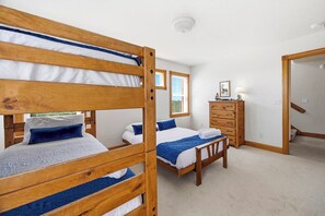 Een kamer met stapelbedden, een dressoir en een raam met jaloezieën.