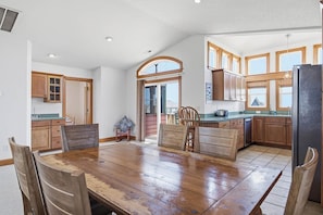 Una cocina amplia con armarios de madera, una gran mesa de comedor y una vista a través de un arco.