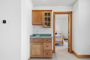 Une petite cuisine avec des meubles en bois, un plan de travail vert et un évier encastré.