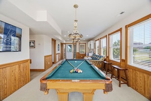 Een pooltafel met ballen, een kroonluchter en houten lambrisering.