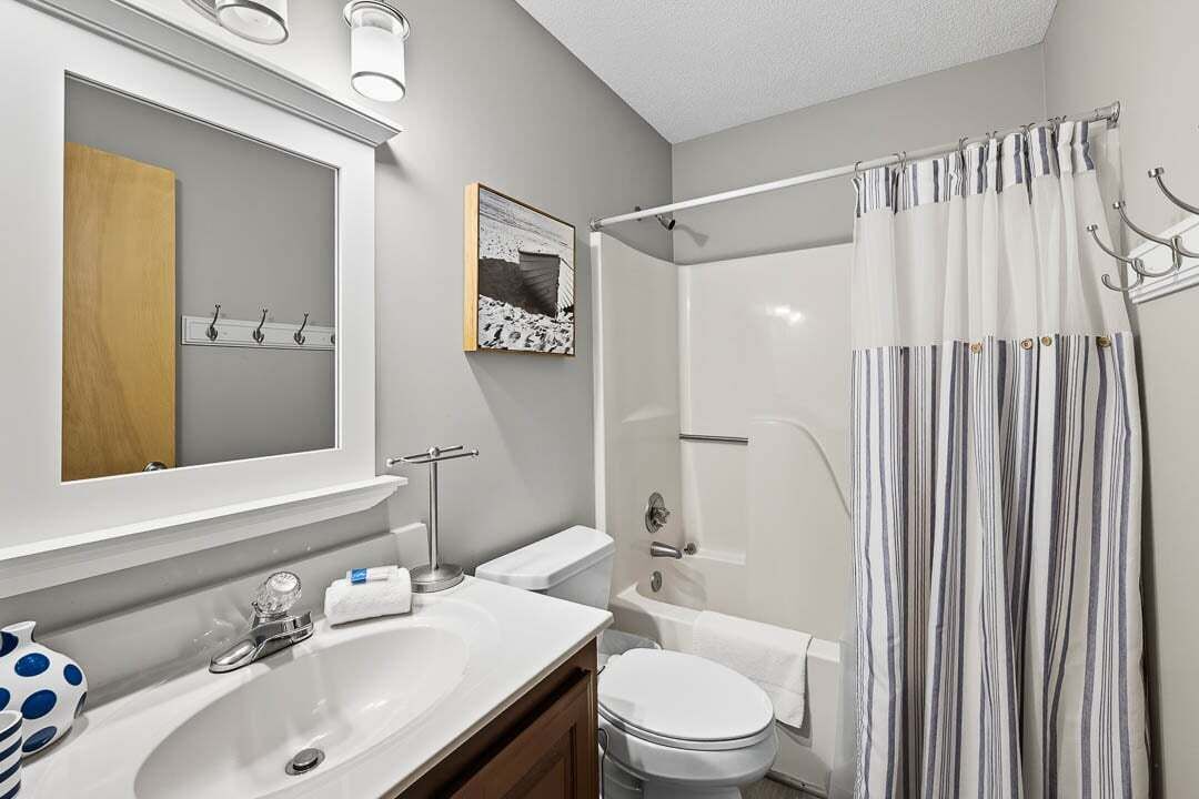 A modern bathroom with a sink, mirror, toilet, and shower.
