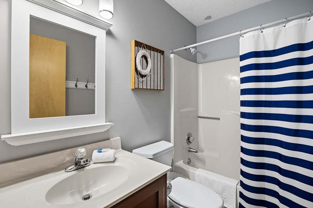 Een badkamer met een witte wastafel, een spiegel, een toilet en een douchegordijn.