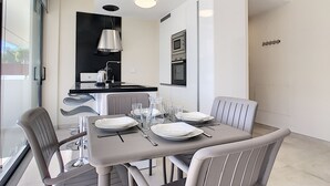 Cozinha moderna com eletrodomésticos embutidos e área de jantar com mesa posta para quatro pessoas.