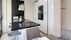 Uma cozinha moderna com bancada preta, eletrodomésticos de aço inoxidável e forno embutido.