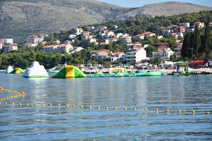 Una zona sul lungomare con strutture gonfiabili e una collina residenziale sullo sfondo.