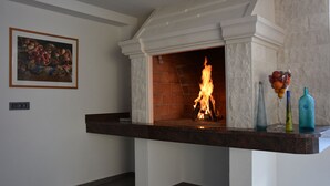 A fireplace with a brick interior, a white mantel, and a dark stone countertop below. - Villa Portofino (Okrug)