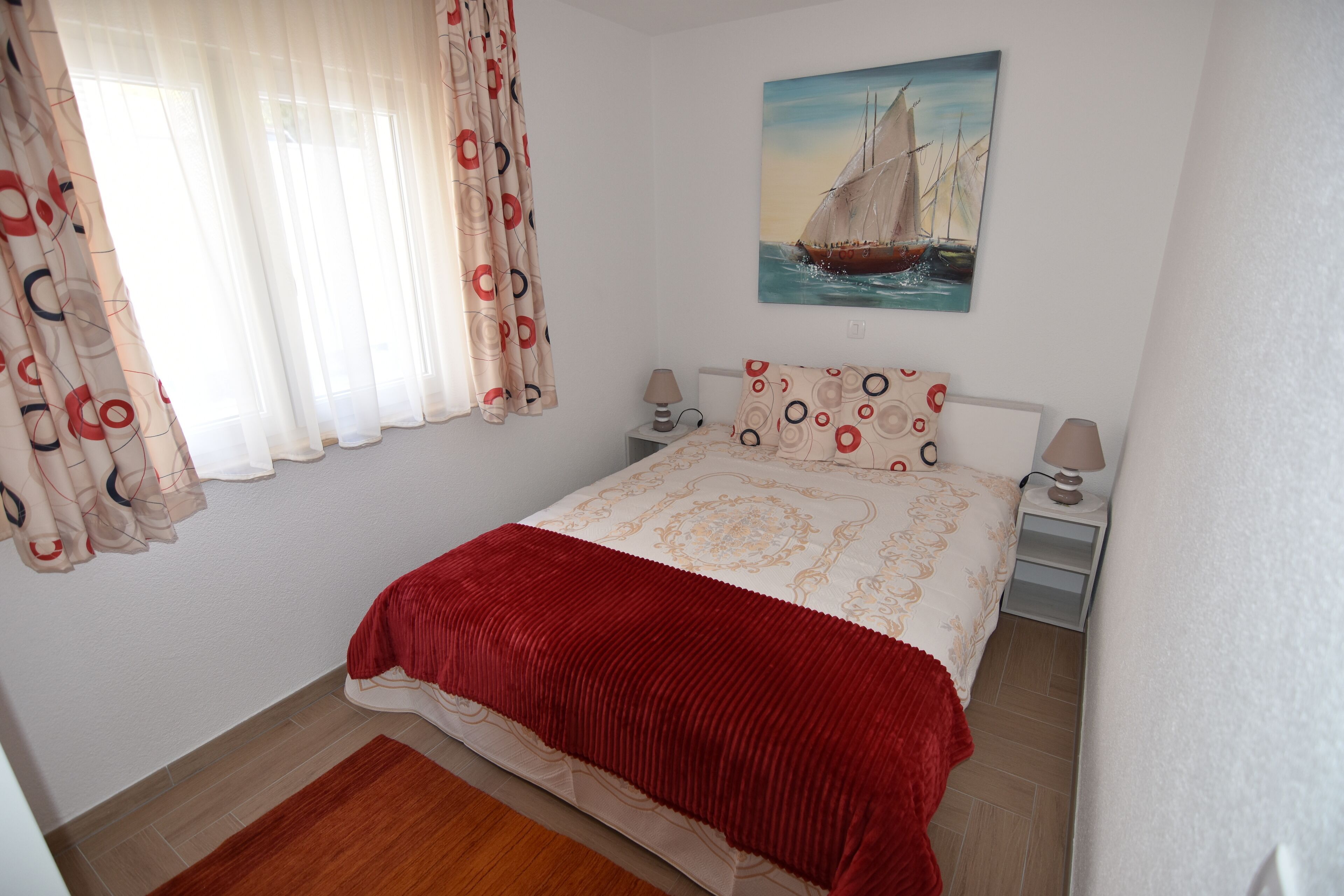 Une chambre à coucher avec un lit, des rideaux, un tableau et une table de chevet.
