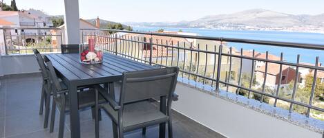 A balcony with a table and chairs, overlooking a scenic view of a body of water and distant hills.