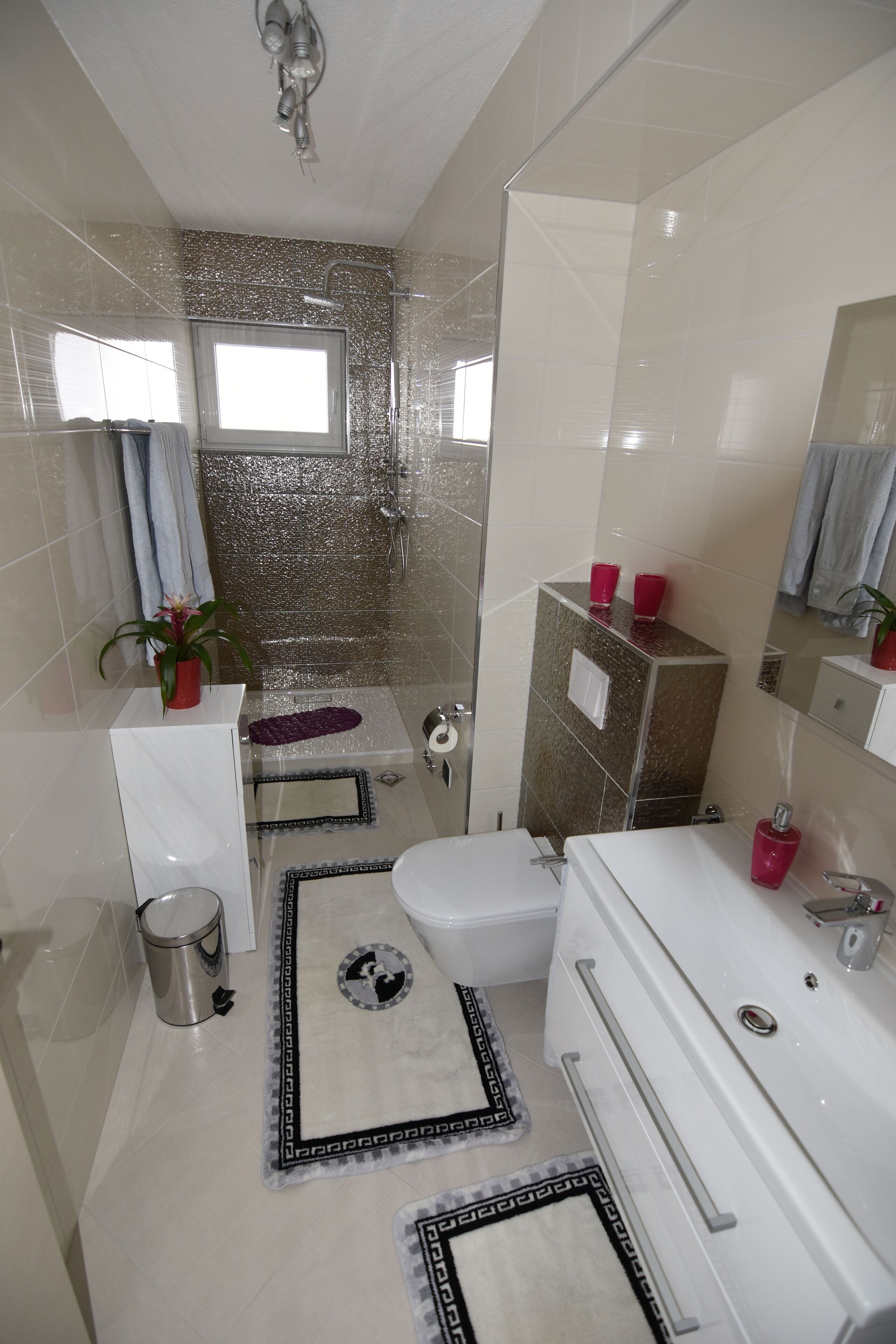 A bathroom with a shower, toilet, bidet, and a sink.