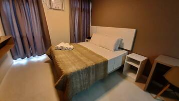 Une chambre d’hôtel avec un lit, une table de chevet, un bureau et une chaise.