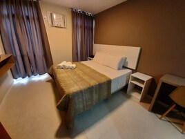 A hotel room with a bed, a nightstand, a desk, and a chair.