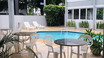 Una piscina al aire libre, sillones reclinables de piscina