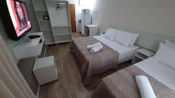 Habitación de hotel con dos camas, televisión, armario y escritorio.