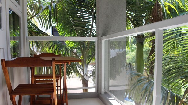 Una habitación con una mesa y sillas de madera, ventanas amplias con vista a palmeras.