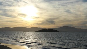 Una playa con vista a montañas y una pequeña isla en la distancia.
