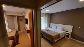Una habitación de hotel con cama, mesita de noche y vistas al exterior.