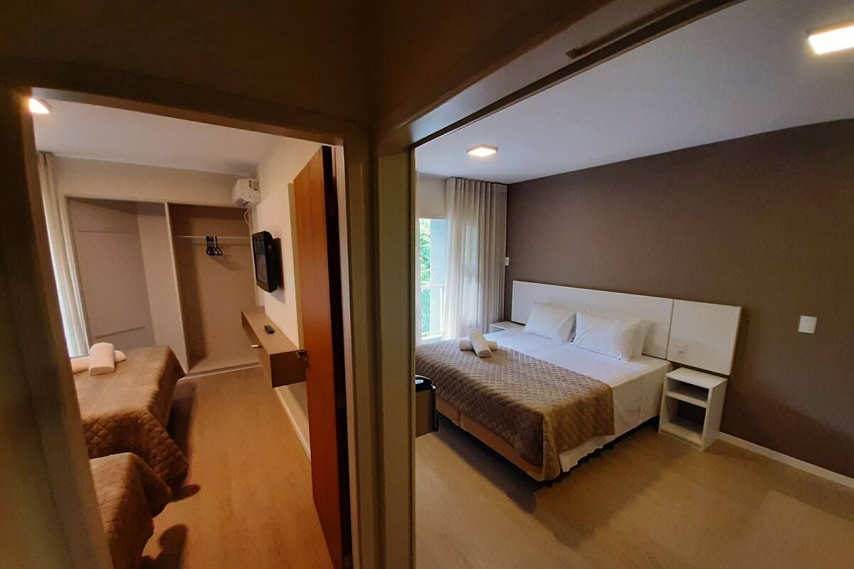 A hotel room with a bed, bedside table, and a view of the outdoors.