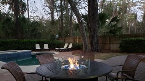 A circular outdoor seating area with a fire pit in the center, surrounded by wicker chairs.