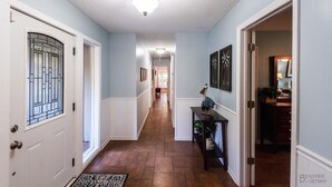 A hallway with a wooden floor, white doors, and a ceiling light fixture.