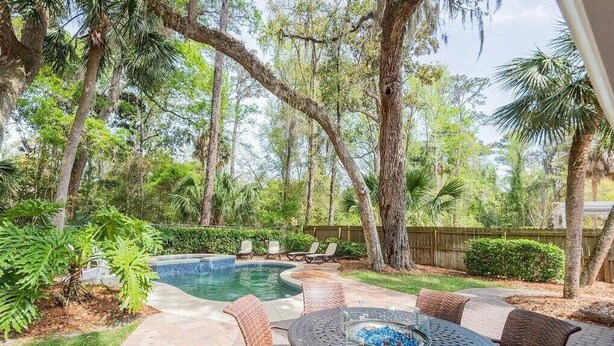 A backyard with a swimming pool, patio furniture, and a fire pit.
